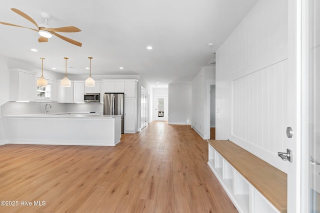 kitchen featuring a peninsula, white cabinets, light countertops, appliances with stainless steel finishes, and light wood-type flooring