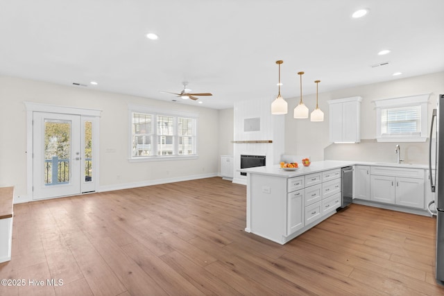 kitchen featuring light wood-type flooring, visible vents, a fireplace, and a peninsula