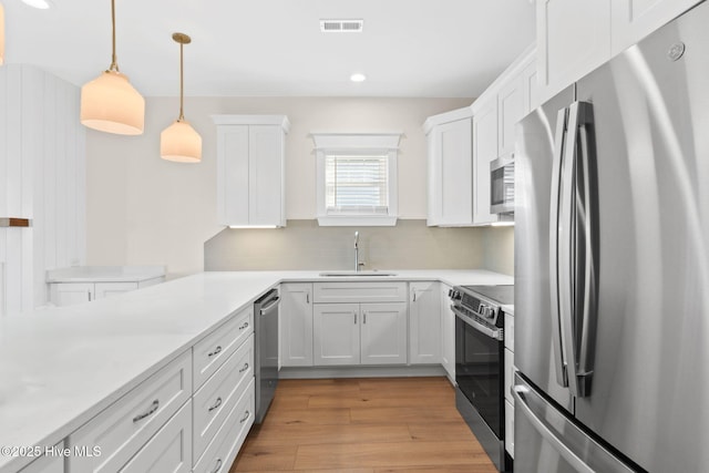 kitchen featuring light wood-type flooring, white cabinetry, stainless steel appliances, and a sink