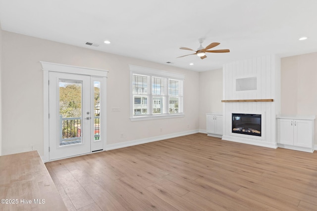 unfurnished living room featuring baseboards, recessed lighting, a fireplace, and light wood-style floors