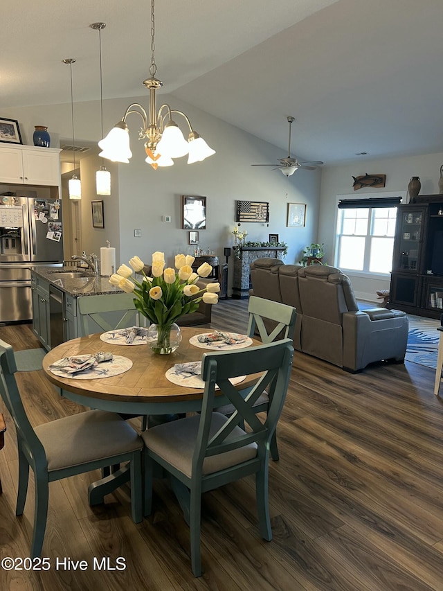 dining space featuring ceiling fan with notable chandelier, dark wood-type flooring, and vaulted ceiling