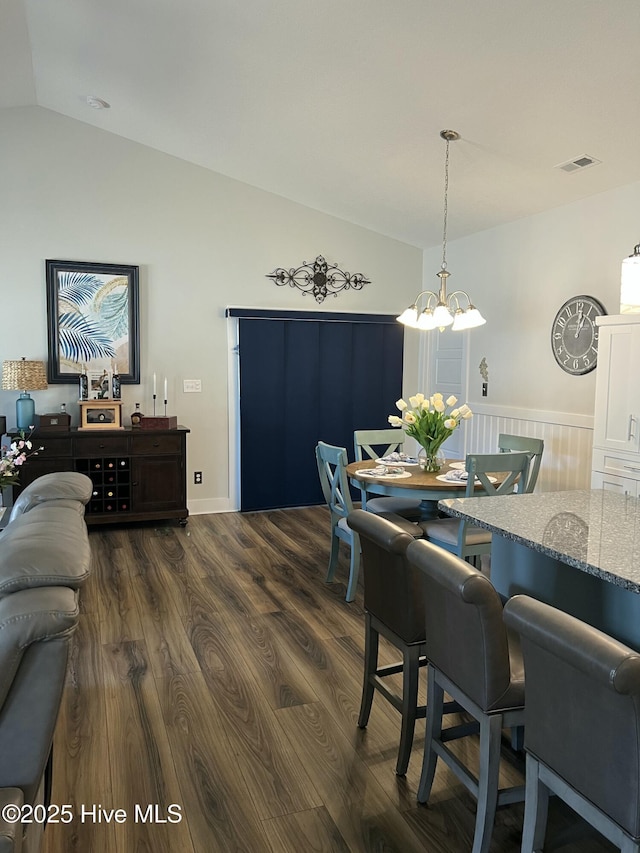 dining area with lofted ceiling, dark wood-style floors, visible vents, and a chandelier