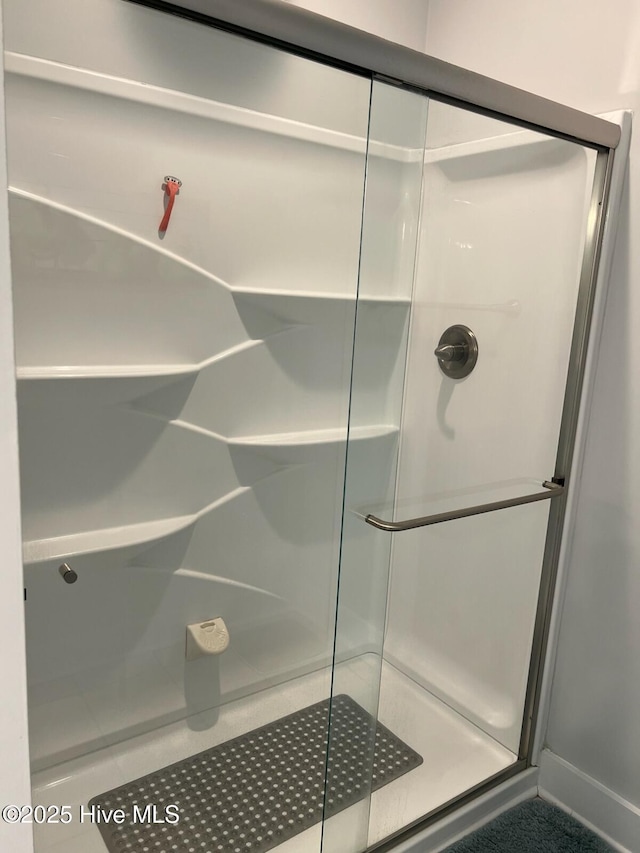 bathroom featuring baseboards and a shower stall