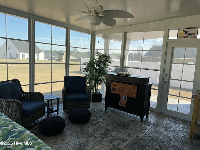 sunroom / solarium featuring plenty of natural light, a ceiling fan, and a residential view