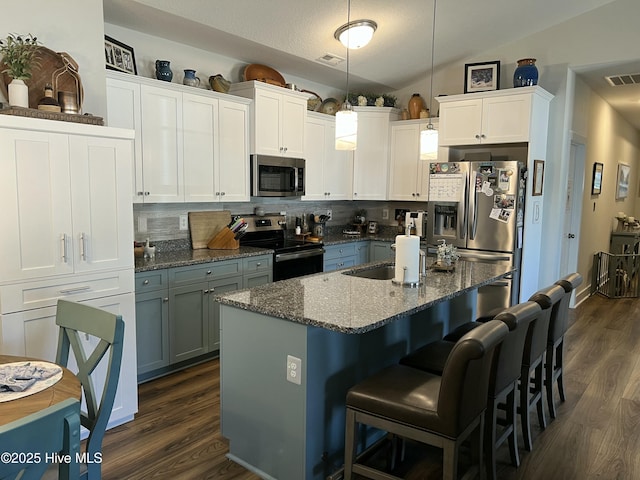 kitchen with dark wood finished floors, visible vents, stainless steel appliances, and lofted ceiling