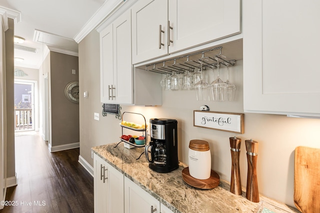 bar with ornamental molding, dark wood-type flooring, visible vents, and baseboards