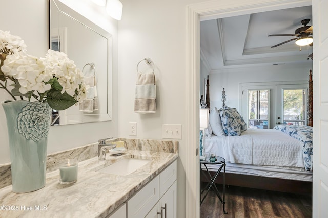 bathroom with wood finished floors, ensuite bathroom, a tray ceiling, crown molding, and vanity