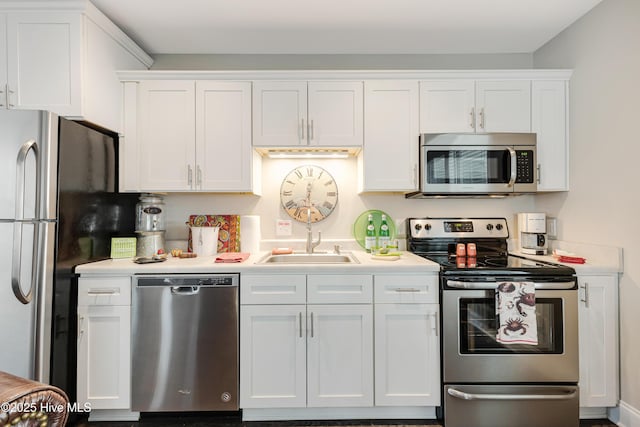 kitchen with stainless steel appliances, light countertops, a sink, and white cabinetry