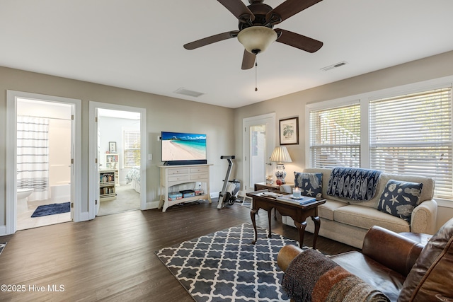 living room featuring baseboards, ceiling fan, visible vents, and wood finished floors