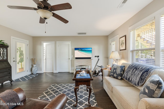 living room with ceiling fan, dark wood-style flooring, visible vents, and baseboards