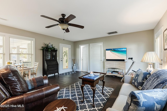 living room with baseboards, ceiling fan, visible vents, and dark wood-style flooring