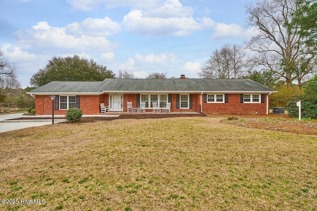 single story home featuring brick siding, a chimney, and a front lawn