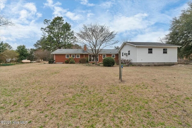 exterior space featuring brick siding, a lawn, and a chimney