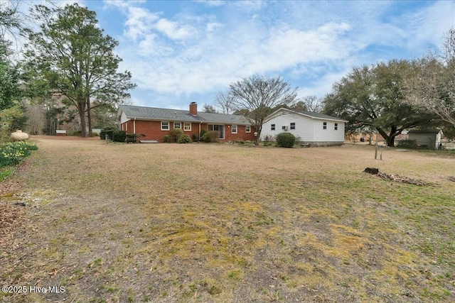 view of front of property featuring brick siding, a chimney, and a front yard