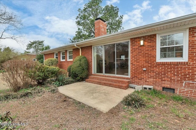 back of house with crawl space, entry steps, a chimney, and brick siding