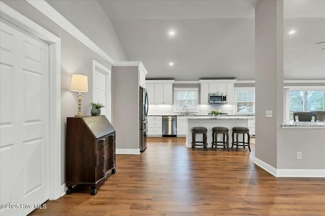 kitchen with a breakfast bar area, a sink, white cabinets, appliances with stainless steel finishes, and backsplash