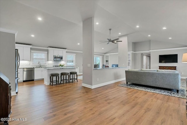 living room featuring light wood finished floors, recessed lighting, baseboards, and a ceiling fan