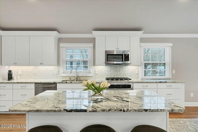 kitchen featuring a center island, crown molding, a breakfast bar area, appliances with stainless steel finishes, and a sink