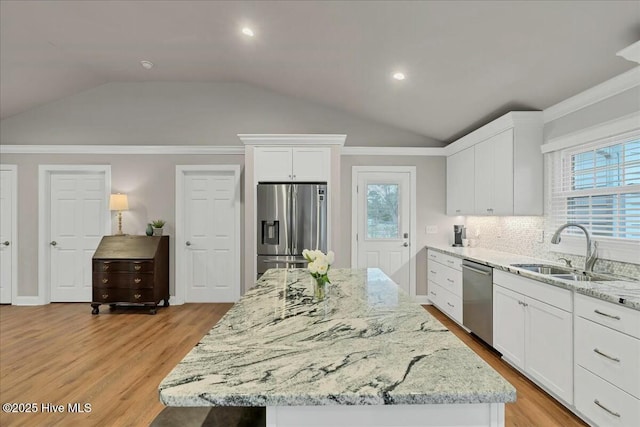 kitchen featuring light wood-style flooring, a sink, white cabinetry, appliances with stainless steel finishes, and vaulted ceiling