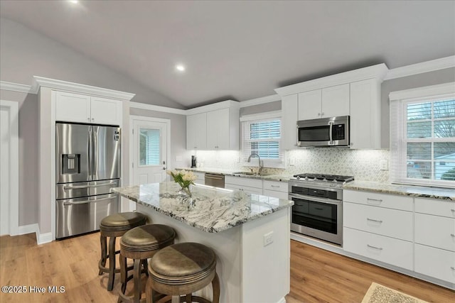 kitchen featuring a kitchen island, white cabinets, stainless steel appliances, and a sink