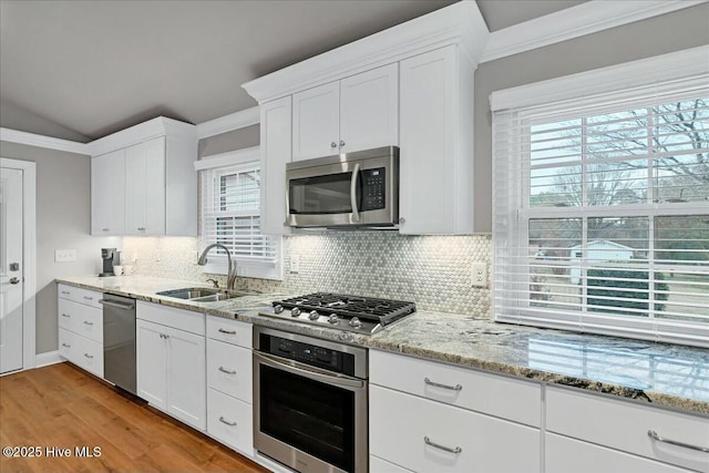 kitchen featuring tasteful backsplash, stainless steel appliances, crown molding, and a sink