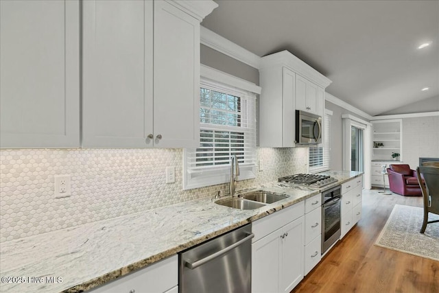 kitchen featuring lofted ceiling, appliances with stainless steel finishes, wood finished floors, white cabinetry, and a sink