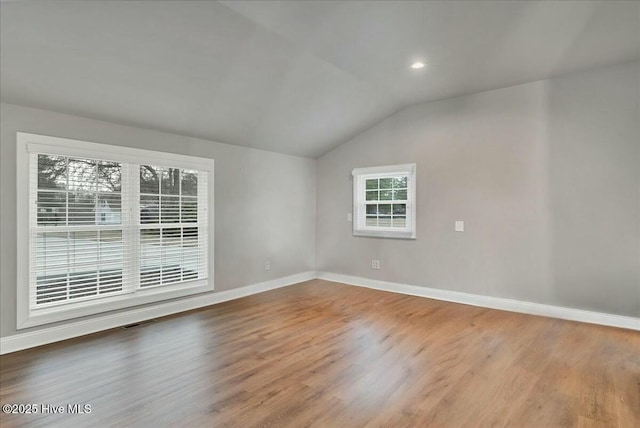 empty room with lofted ceiling, wood finished floors, visible vents, and a healthy amount of sunlight