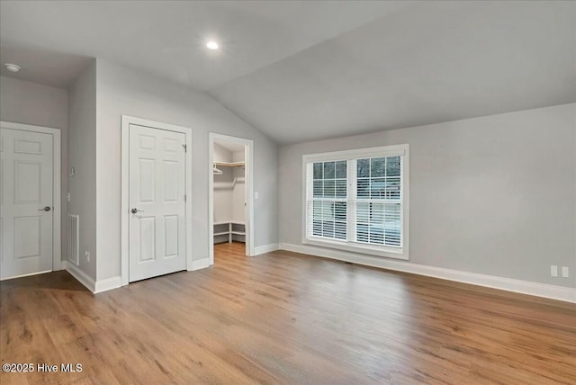 unfurnished bedroom featuring visible vents, baseboards, wood finished floors, and vaulted ceiling