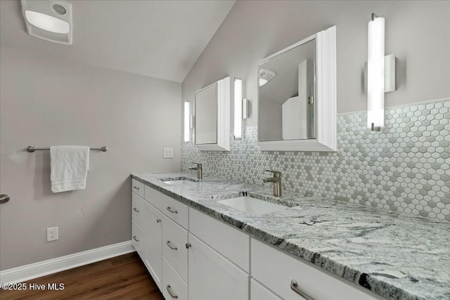 bathroom featuring double vanity, vaulted ceiling, decorative backsplash, and a sink