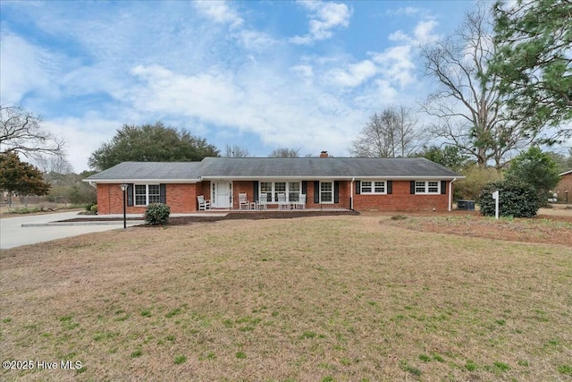 ranch-style house featuring brick siding, a porch, a chimney, and a front lawn