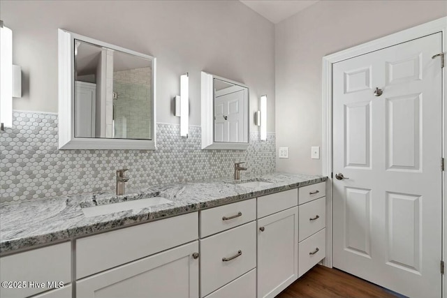 full bathroom with double vanity, wood finished floors, backsplash, and a sink