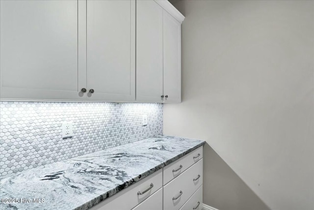 kitchen with decorative backsplash, white cabinets, and light stone countertops