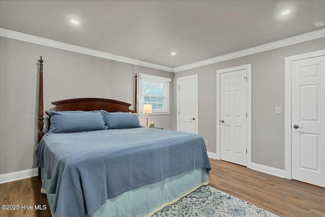 bedroom with wood finished floors, baseboards, two closets, and ornamental molding