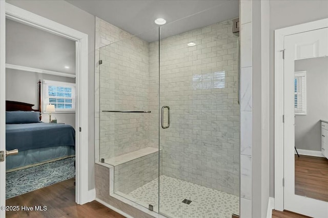 ensuite bathroom with baseboards, a shower stall, wood finished floors, and ensuite bathroom