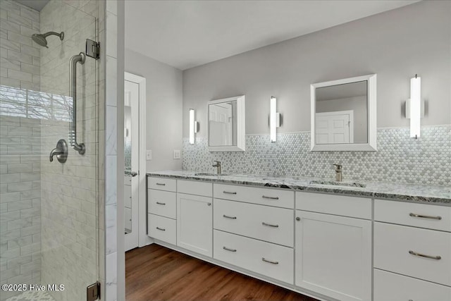 full bathroom featuring a shower stall, wood finished floors, tasteful backsplash, and a sink