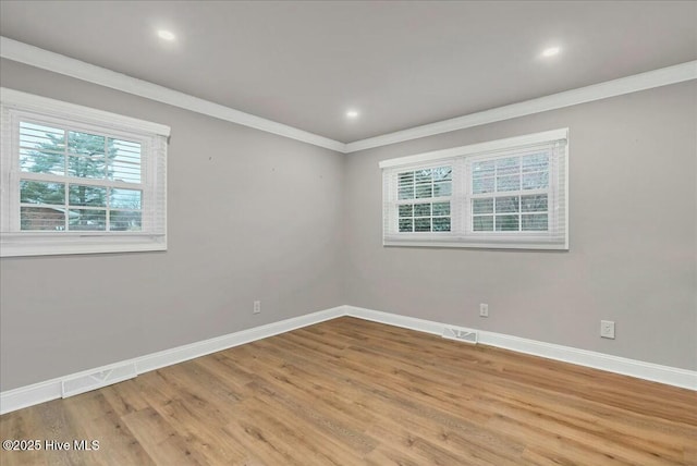 spare room featuring crown molding, wood finished floors, baseboards, and visible vents