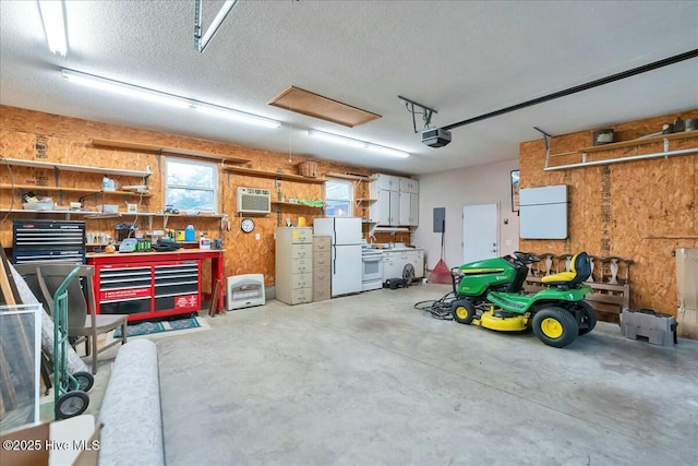 garage featuring a wall unit AC, refrigerator, freestanding refrigerator, a workshop area, and a garage door opener