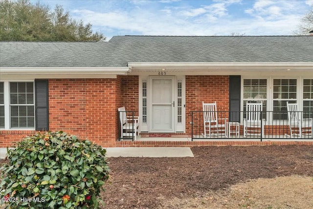 property entrance with brick siding and roof with shingles