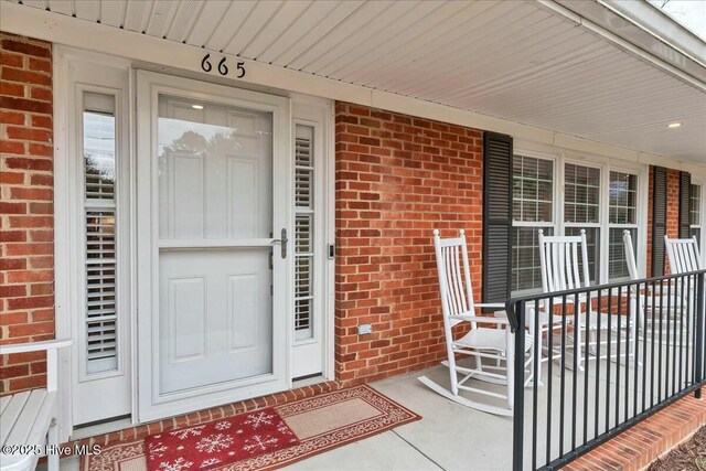 property entrance featuring brick siding and covered porch