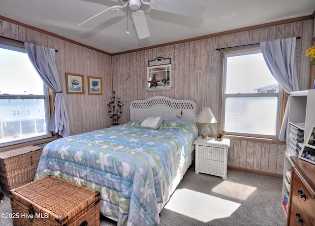 carpeted bedroom featuring wooden walls, a ceiling fan, and crown molding