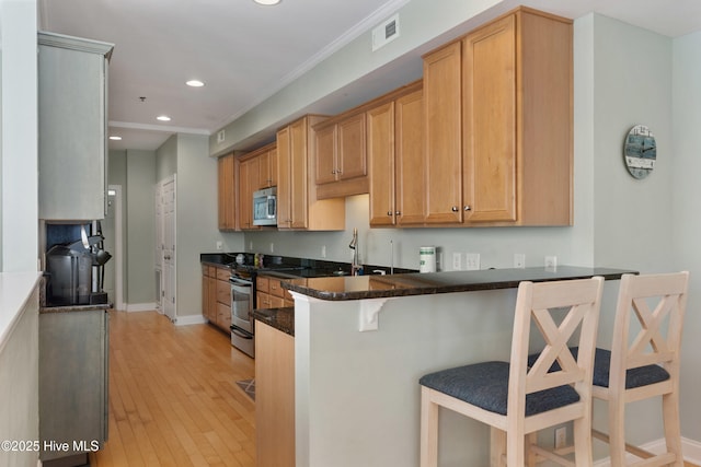 kitchen featuring recessed lighting, stainless steel appliances, a peninsula, visible vents, and a kitchen breakfast bar