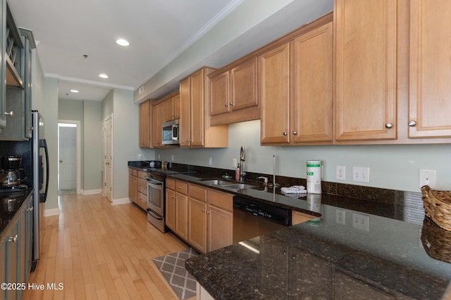 kitchen with crown molding, appliances with stainless steel finishes, light wood-style floors, a sink, and dark stone countertops