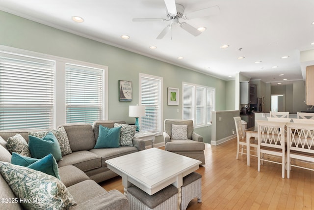 living area with light wood finished floors, baseboards, a ceiling fan, ornamental molding, and recessed lighting