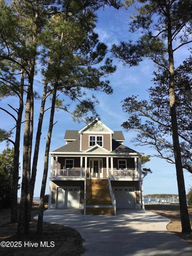 view of front of home with driveway, a shingled roof, stairway, an attached garage, and covered porch