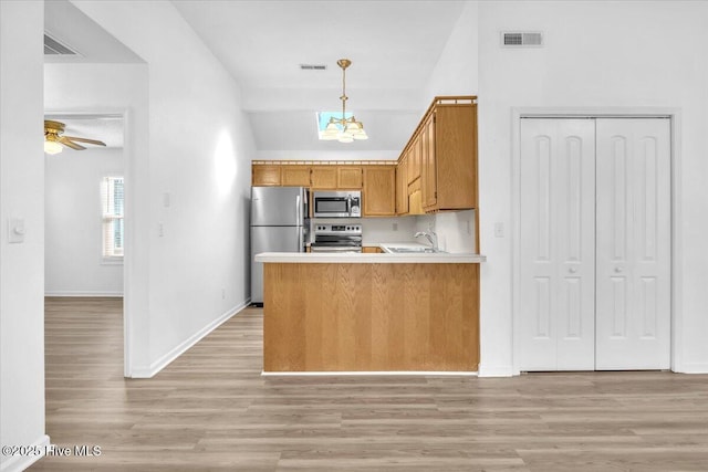 kitchen with stainless steel appliances, a sink, visible vents, light wood-type flooring, and brown cabinets