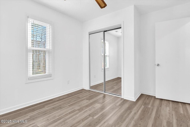 unfurnished bedroom featuring ceiling fan, a closet, baseboards, and wood finished floors