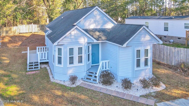 view of front of house with a shingled roof, a front yard, and fence