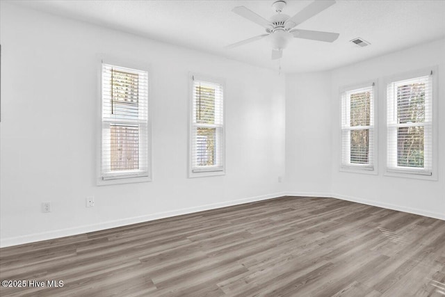 spare room with a ceiling fan, baseboards, visible vents, and wood finished floors