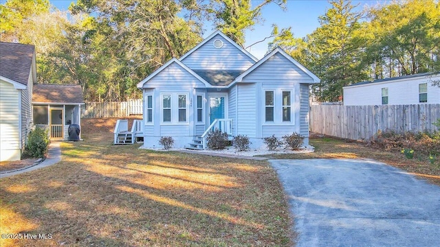 bungalow-style home with a front lawn and fence