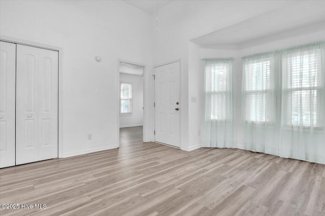 unfurnished bedroom featuring baseboards, a closet, and light wood-style floors